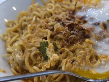 İştah açıcı yakın çekim yağda yumurta, yeşil sebze ve gevrek arpacık soğanı ile kaplanmış kremalı erişteyi yakalayıp yemeye hazır hale getirir.