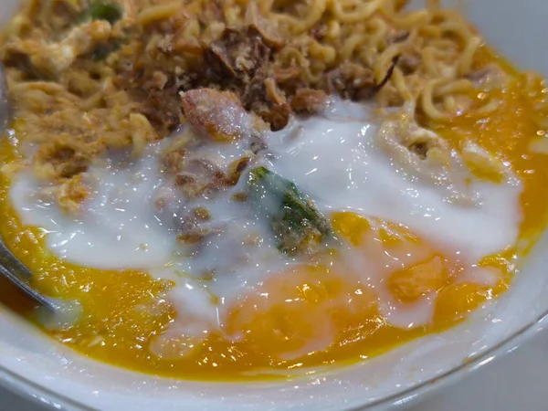 Mükemmel pişmiş yumurta sarısı ve lezzetli çıtır çıtır soslu, beyaz bir kasede servis edilen sıcak erişteye yakın.