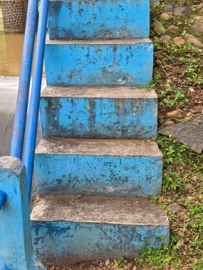 Eski, yıpranmış mavi, beton merdivenler, toprak ve yosun.