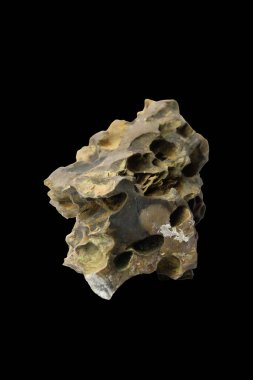 İçinde doğal delikler ve derin yarıklar bulunan küçük ejderha taşı kesme yolu olan siyah bir arka planda izole edilmiş..