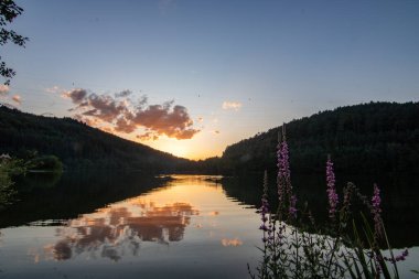 Bir göl kıyısının manzara görüntüsü. Göz kamaştırıcı renklerle bir yaz günbatımı. Marbach Reservoir, Hesse, Almanya
