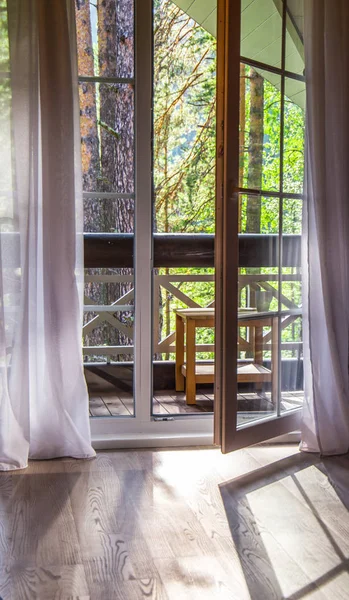 Französische Türen öffnen sich auf einen Balkon mit Blick auf grüne Bäume. Natur. Relax Konzept. Berufungen Stockbild