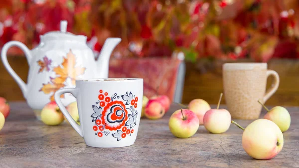 Tasse de thé avec feuilles d'automne et pommes sur table en bois — Photo