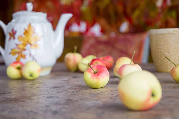 Cup of tea with autumn leaves and apples on wooden table — Stock Photo, Image