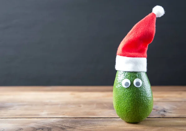 Weihnachten Avocado. Avocado in Weihnachtsmütze. Urlaubskonzept Stockfoto