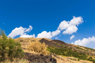 Yolu seyret. Siyah volkanik kum, volkanik taşlar, orman manzarası. Taormina. Sicilya. Dağlarda ve bulutlarda orman. Yer, bitkiler, bulutlar, sonbahar günü