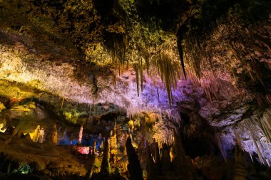 İspanya 'da Mallorca adasındaki Stalactite aydınlatmalı mağaralar. Mağaraların çok renkli aydınlatması. Güzel mağara. Eski mağaradaki sarkıtlar. Kırmızı, yeşil, mavi, mor, sarı.