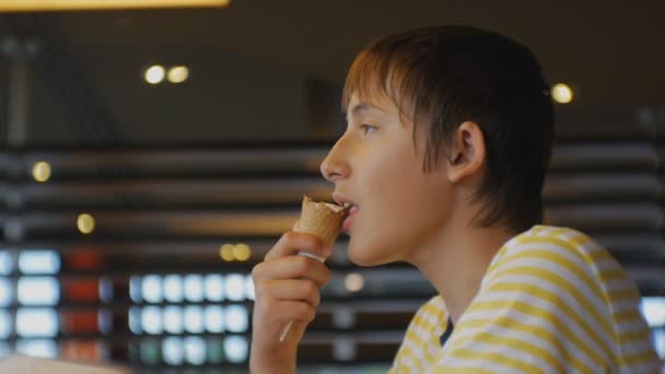 Adolescente comendo fast food. close-up tiro de adolescente menino comer sorvete cone no fast food restaurante . — Vídeo de Stock