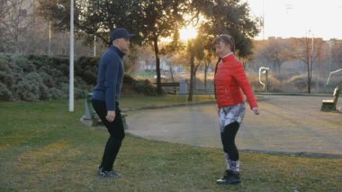 Kişisel antrenör açık havada ile egzersiz. Karşılıklı parkta günbatımında egzersiz genç çekici kadın ve fitness eğitmeni hamle yapıyor. Egzersiz uygun formu gösteren koç