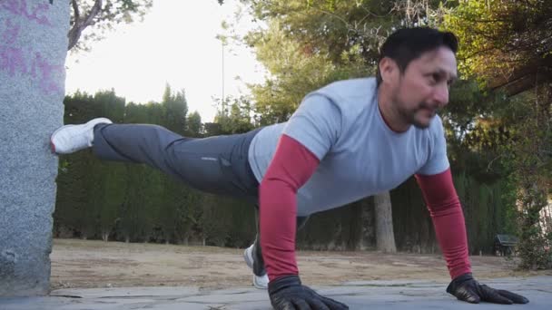 Träning med personlig tränare utomhus. Fitness man gör lyfte benet armhävningar i en park som en del av en workout rutin. — Stockvideo