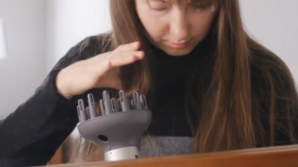 Primer plano de la atractiva mujer de cabello castaño poniendo su cabello en difusor delante del espejo en casa . — Vídeos de Stock