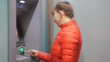Para kullanan kadın. Çekici genç bayan kırmızı balonu ceketli kredi kartı Atm. girerek PIN kodu gülümseyen kadın ekleme.