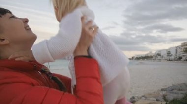 Akşam deniz bebek çekici kadın. Anne kucağında bebek kız yetiştirme ve deniz kıyısında arka plan üzerinde öpüşme Close-up. Mutlu çocukluk ve Aile kavramı.