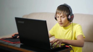 Dizüstü bilgisayar kullanmayı gece zaman genç. Klavye tuşuna basarak defter perde yapıştırılmış kulaklıklarla teen video oyunu bağımlısı.