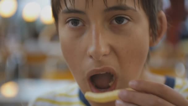 Adolescente comiendo comida rápida. Primer plano de caucásico adolescente mordiendo y masticando papas fritas al aire libre . — Vídeos de Stock