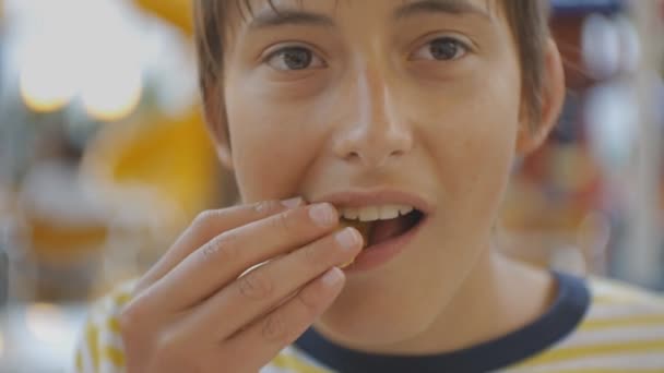 Adolescente comiendo comida rápida. Primer plano de caucásico adolescente mordiendo y masticando pepitas al aire libre . — Vídeo de stock