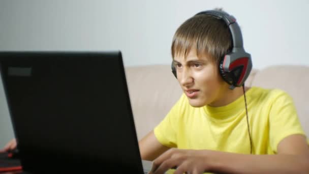 Подросток, играющий ночью в видеоигры. Компьютерный наркоман подросток с наушниками недовольный игрой смотрит на экран ноутбука . — стоковое видео