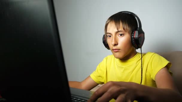 Tiener met behulp van laptop op moment van de nacht. Computer verslaafd tiener jongen met een poker gezicht kijken naar het laptopscherm op het toetsenbord te drukken. — Stockvideo