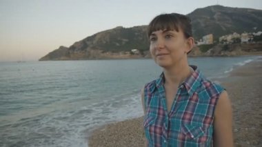 Çekici beyaz çakıl plajı deniz boyunca yürürken ekose mavi gömlek gülümseyen.