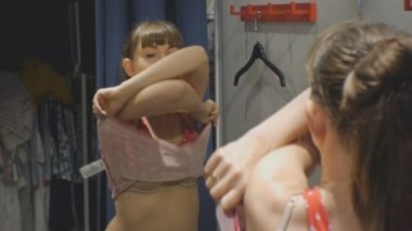 Genç kadın kıyafetlere. Aynaya oda uygun giyim mağazalarında kırmızı gömlek kapalı alarak bej sütyen çekici beyaz kadın görünüyor.