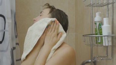 Kadın duş alıyor. Çekici beyaz kadın yüzünü gözler kapanış bir havluyla siliyor..