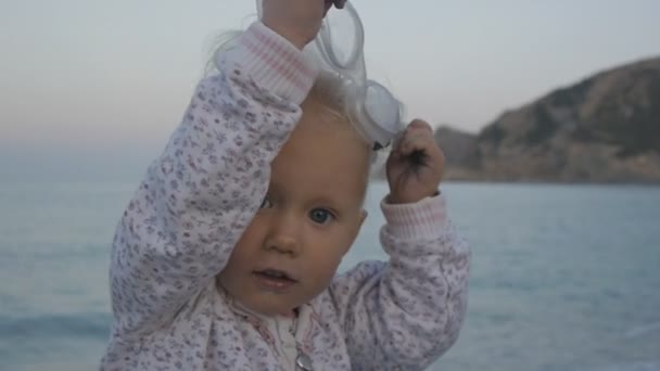 Retrato de travesso branco loira bebê menina decolando óculos de natação no fundo do mar . — Vídeo de Stock