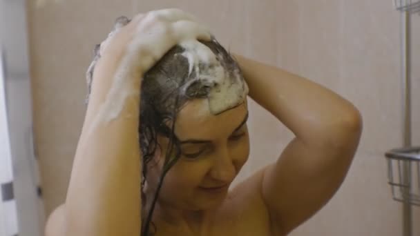 Une femme qui prend une douche. Gros plan de jolie femme caucasienne savonne ses cheveux en appliquant de la mousse de shampooing . — Video