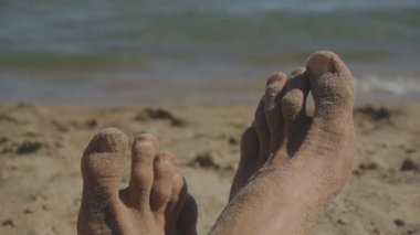 Beyaz adam denize yakın kumlu plajda yatan metrelik Close-up.