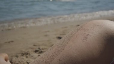 Beyaz kadının kumsal deniz kenarında yatan kalça Close-up.