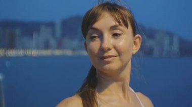 Smartphone ile çekici genç kadın alarak selfie. Kafkas kadın kendi kendine portre fotoğraf veya video telefon ile gece resort şehir ve deniz arka plan üzerinde yapma Close-up.