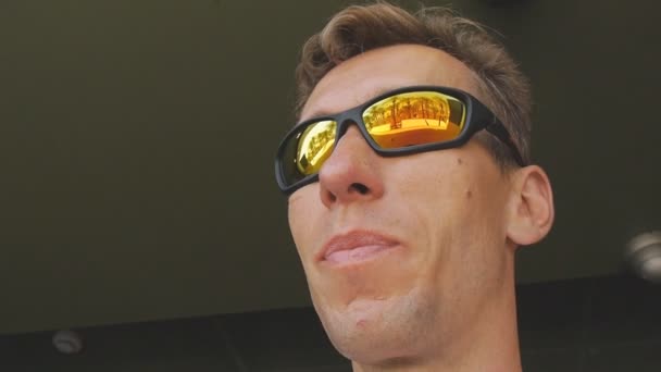 Man eating fastfood. Close-up shot of caucasian male in mirror sunglasses reflecting palm tree beach eating village potatoes in fast food restaurant. — Stock Video