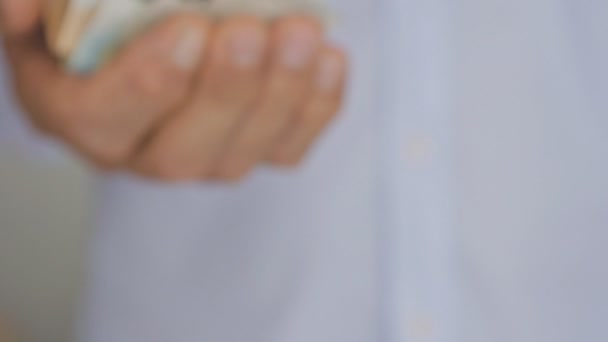 Close-up of a hand of elderly man in a light blue shirt holding out euro notes. — Stock Video