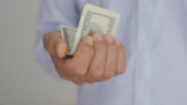 Close-up de uma mão de homem idoso em uma camisa azul claro segurando notas de cem dólares . — Vídeo de Stock