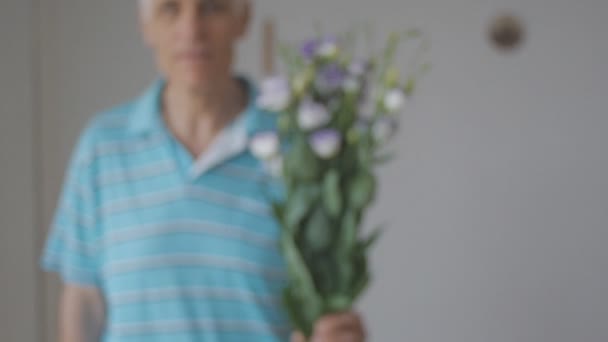 Gray-haired senior man boeket bloemen thuis te geven. Uit focus shot. — Stockvideo