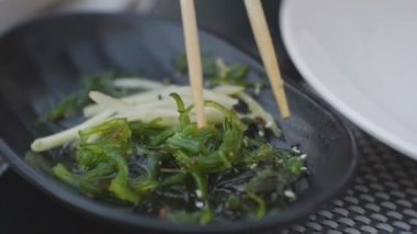 Yakın çekim yemek çubukları tarafından alınan yosun salatası.