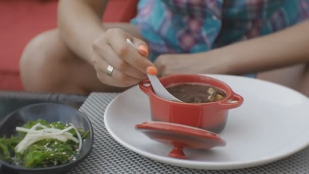 Aantrekkelijke jonge Kaukasische vrouw een soep uit klei pan op open terras van Japanse restaurant proeverij. — Stockvideo