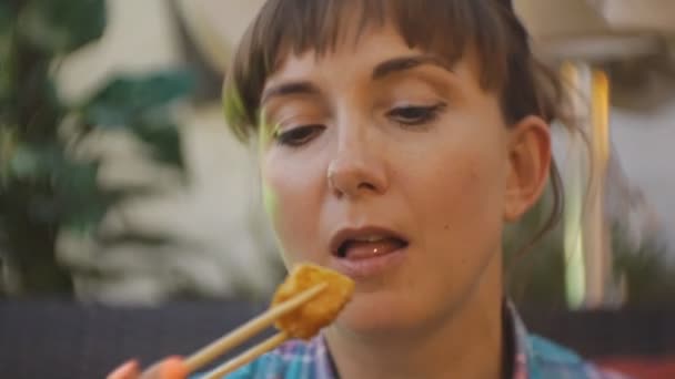 Vrouw probeert Japanse keuken. Close-up van aantrekkelijke jonge Kaukasische vrouw bijten diepe Gebakken tofu, waarbij het met stokjes op het open terras van Japans restaurant. — Stockvideo