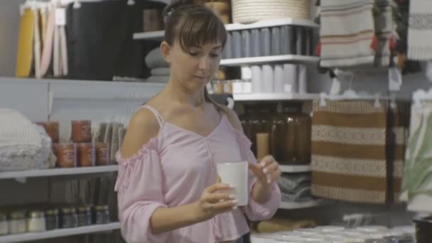 Aantrekkelijke vrouw in huishoudelijke winkel. Kaukasische vrouw ruikt Geurkaars. — Stockvideo