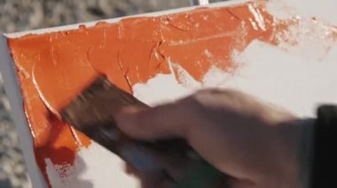 Yakın çekim shot erkek sanatçıların resim modern soyut resim arcrylic boya ve gündoğumu deniz Plajı'nda geniş spatula ile el.