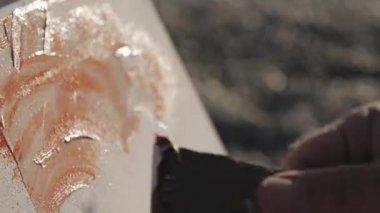 Yakın çekim shot erkek sanatçıların resim modern soyut resim yağlı boya ve gündoğumu deniz Plajı'nda geniş spatula ile el