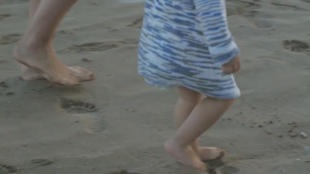 Mulher branca e bebê de dois anos brincando na praia do pôr-do-sol. Mãe e filha correndo deixando pegadas na areia molhada . — Vídeo de Stock