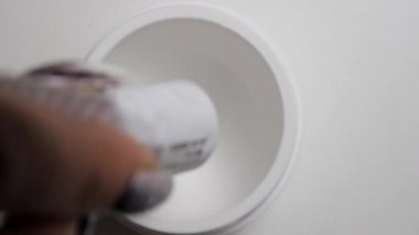 Tüp koyu kahverengi boya beyaz bir kavanoza dışarı sıkma eller Close-up. Kaşlar boyama.