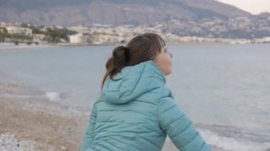 Kadın yalnız soğuk Plajı'nda. Sakin denize taş atan kafkas kadın portresi.