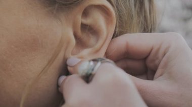 Açık havada el yapımı küpe üzerinde koyarak eller Close-Up.