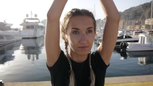 Jonge vrouwen doen oefeningen op zee haven. Close-up van slanke aantrekkelijke Kaukasische meisje het beoefenen van yoga staande met de handen boven het hoofd. — Stockvideo