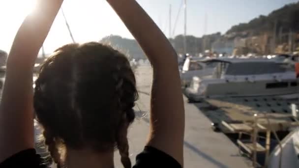 Jonge vrouwen doen oefeningen op zee haven. Spinnen schot van fit aantrekkelijke Kaukasische meisje het beoefenen van yoga staande met de handen boven het hoofd. — Stockvideo