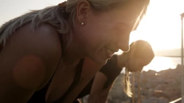 Unga kvinnor gör övningar på havet hamn. Närbild av passa attraktiva kaukasiska kvinnor leende gör yoga andningsövning på sunset beach. — Stockvideo