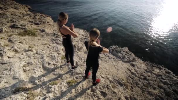 Dwie młode kobiety robią ćwiczenia nad morzem. — Wideo stockowe