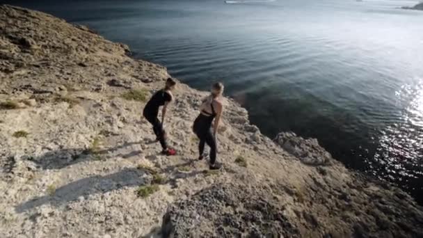 Dos mujeres jóvenes haciendo ejercicios junto al mar . — Vídeos de Stock