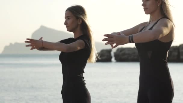 Two young women doing exercises by the sea. — Stock Video